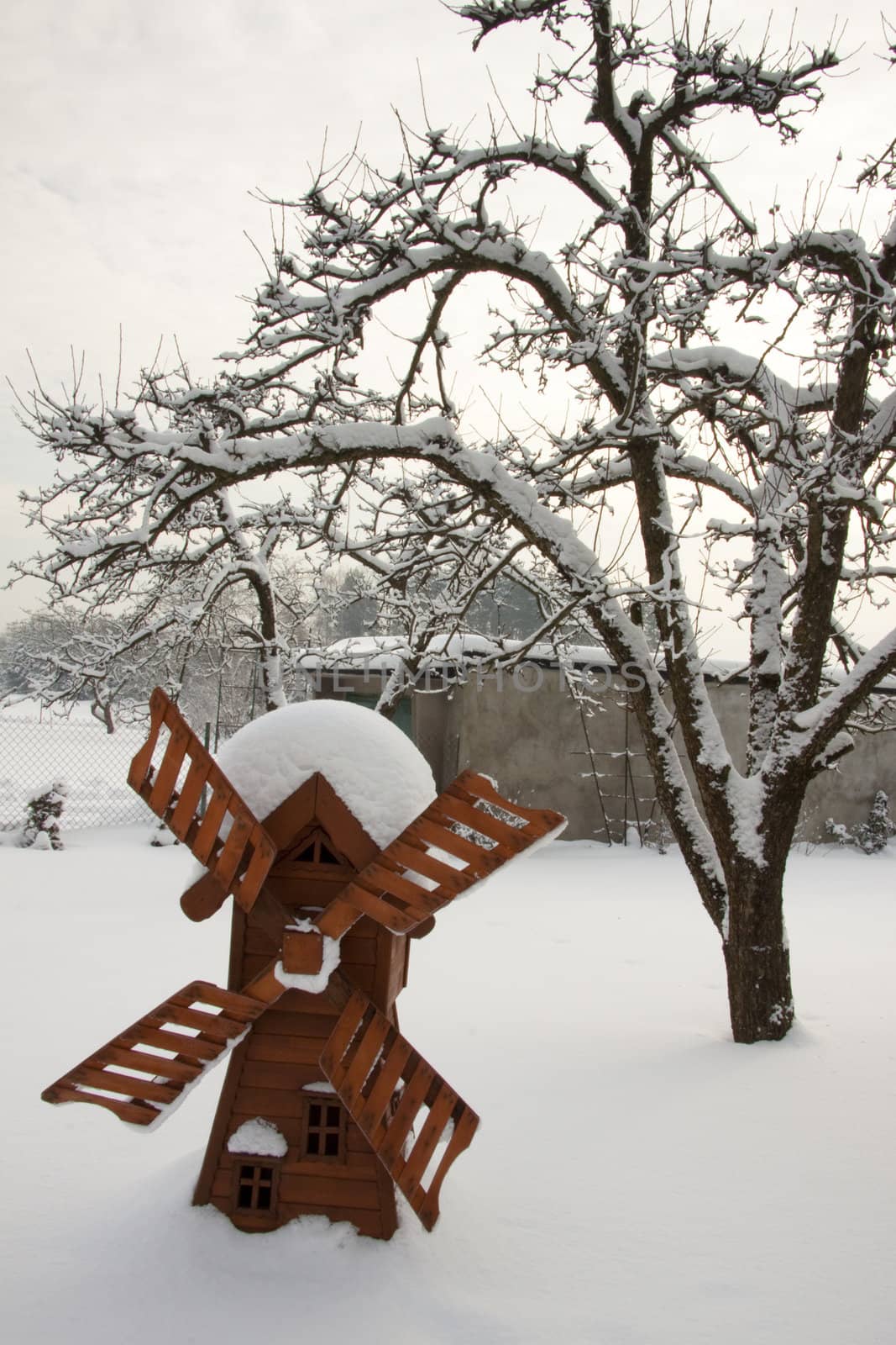 Small wooden windmill in polish garden in winter.