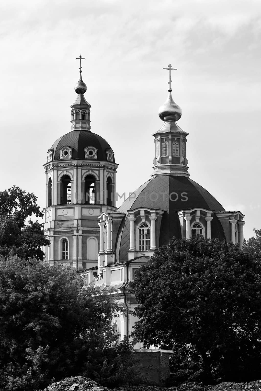 a photo of an Orthodox Church with green walls and golden domes stand behind the trees