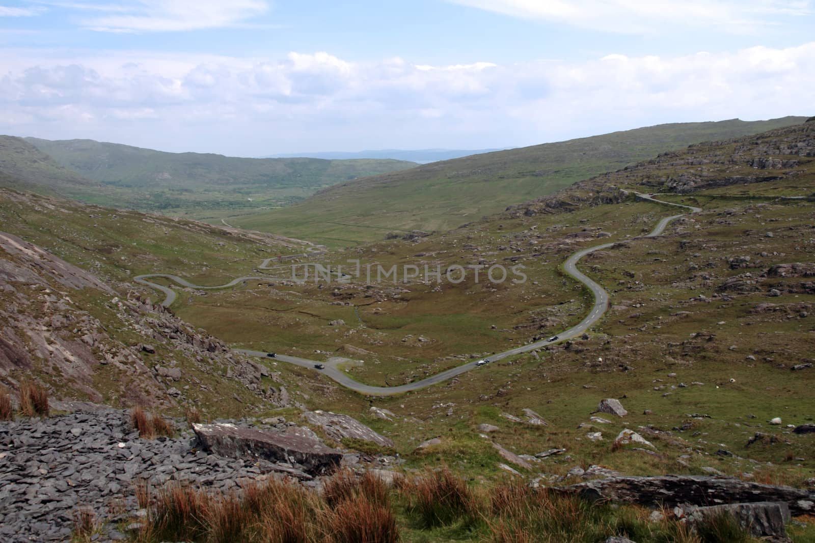 an evening view of winding roads through the mountains of kerry with vintage cars on the roads