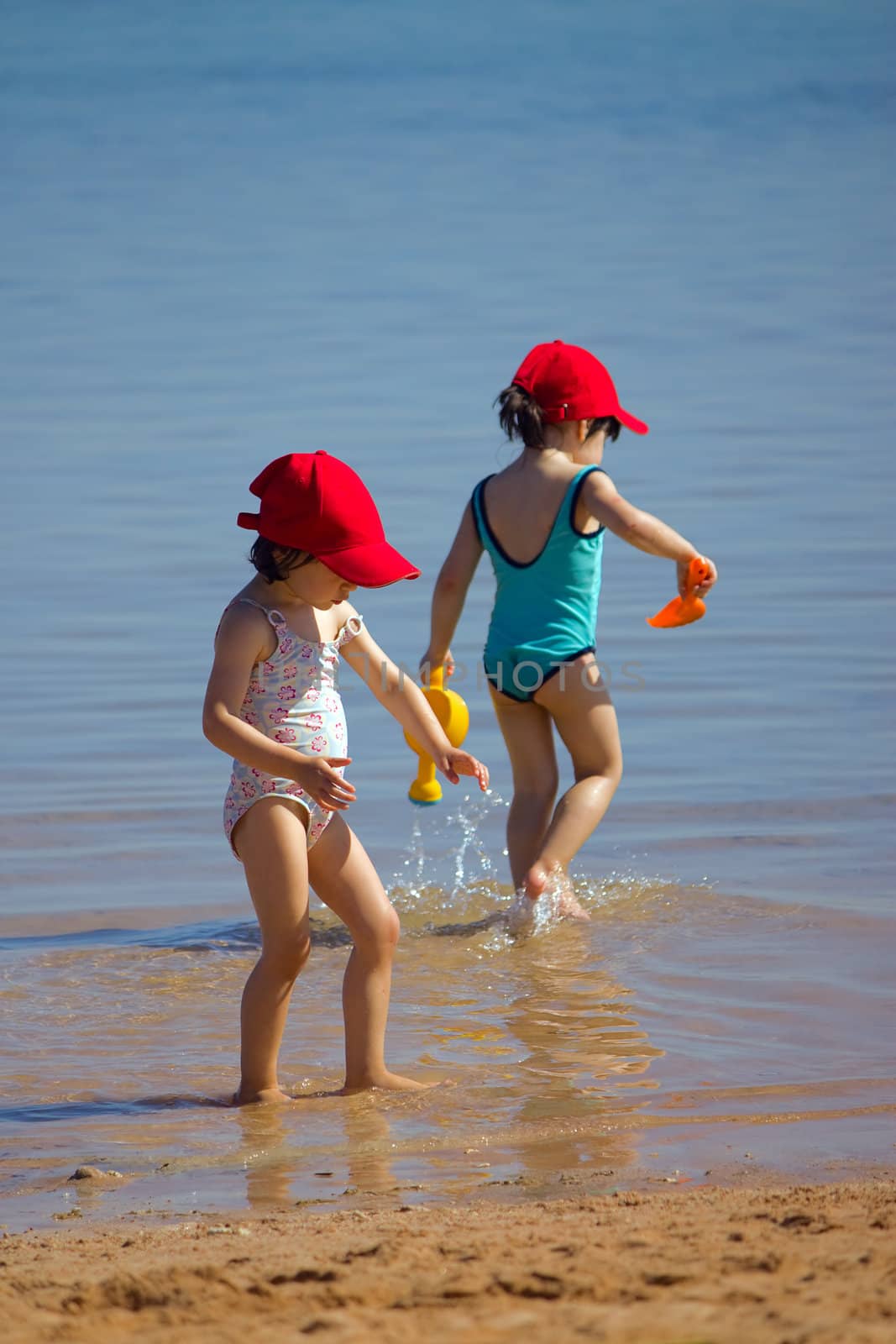 Two little girls playing on the beach.