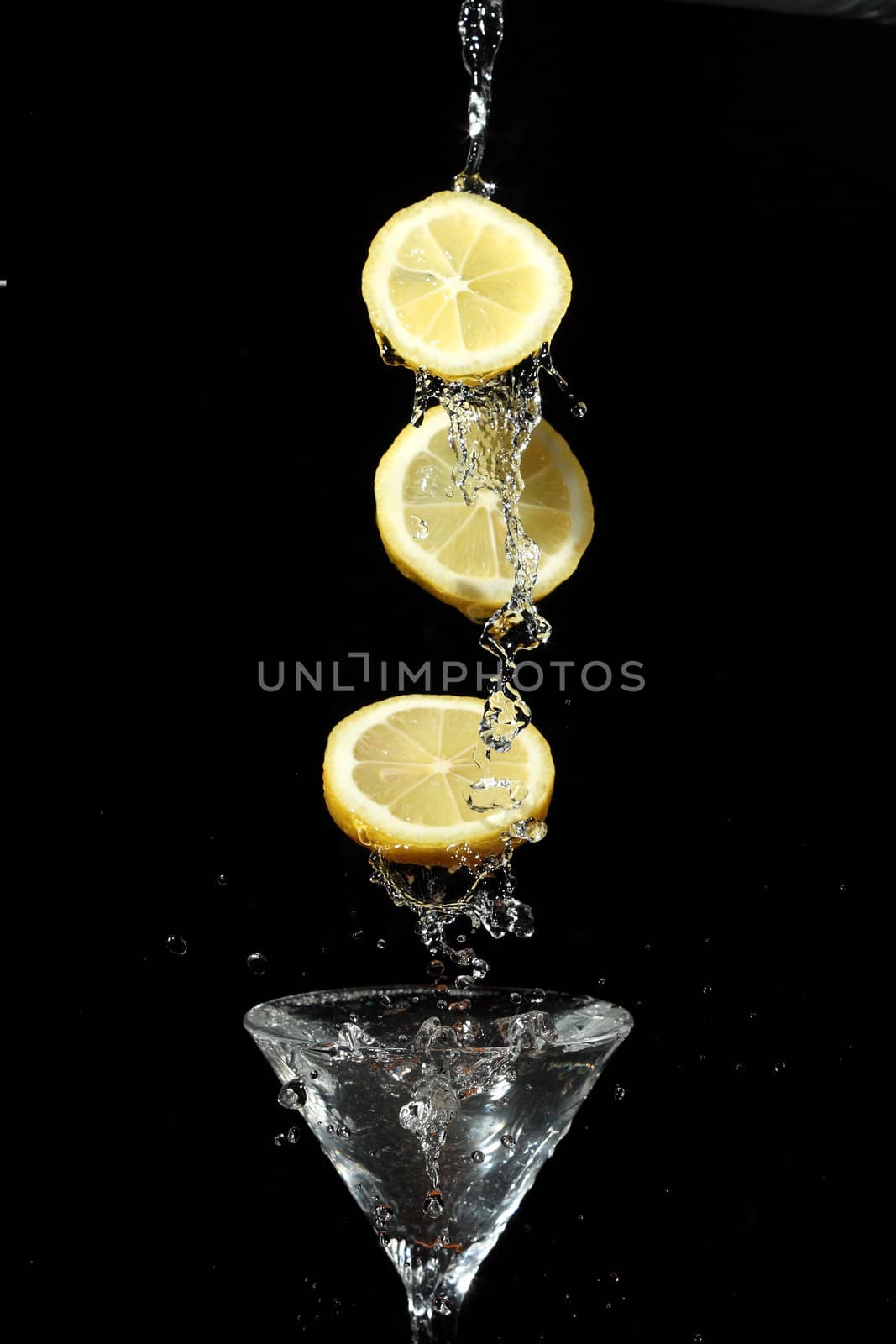 The segments of fruit falling in a glass with a drink