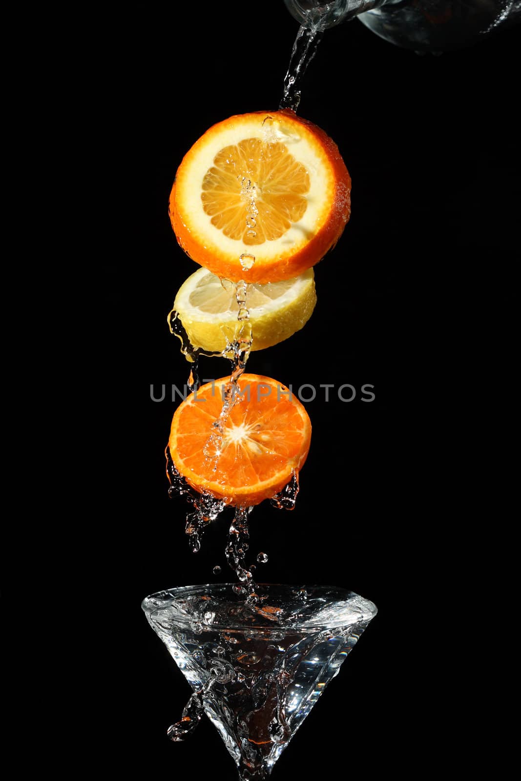 The segments of fruit falling in a glass with a drink