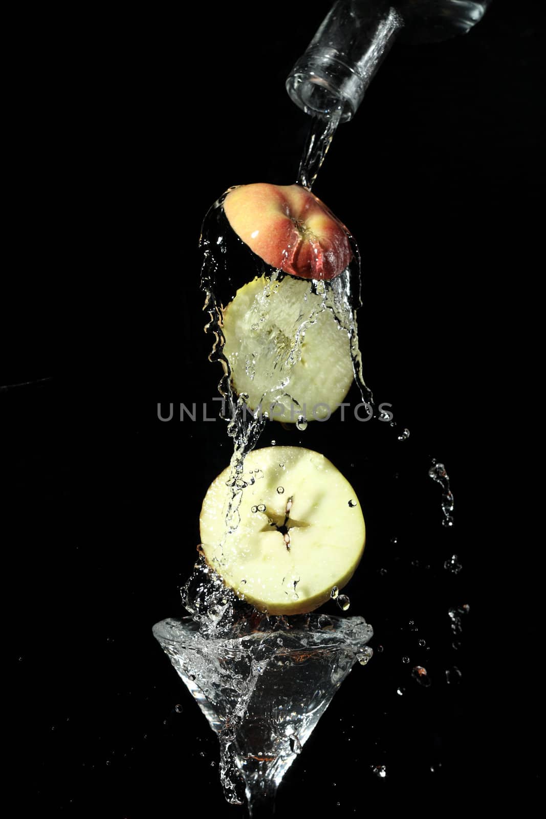 The segments of fruit falling in a glass with a drink
