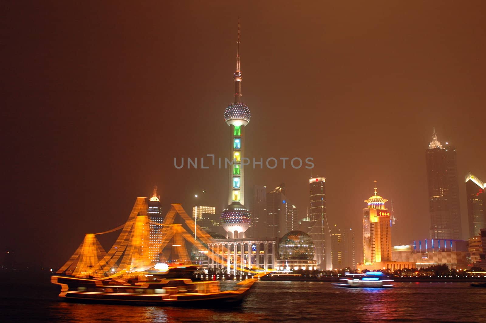 Shanghai city in China. Famous Orient Pearl TV tower with Huangpu River and ship by night.