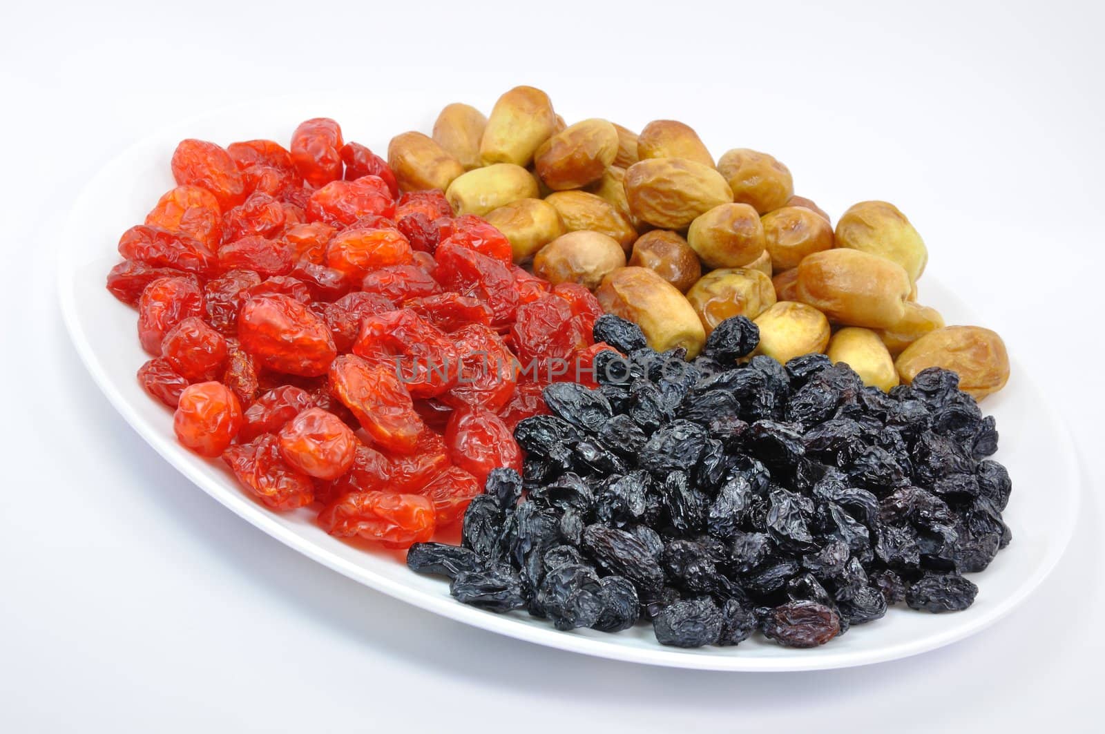 Dried Dates, Cornelian Cherries and Black Raisins on White Plate Isolated