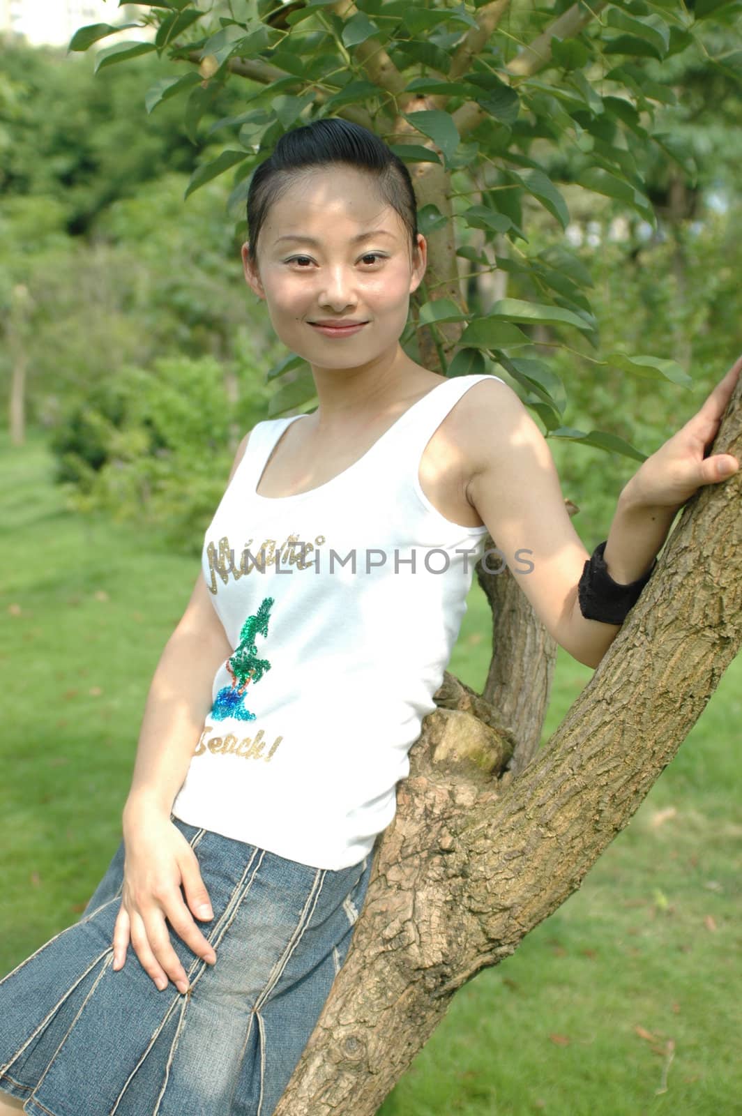 Chinese girl relaxing in park, sitting on tree.
