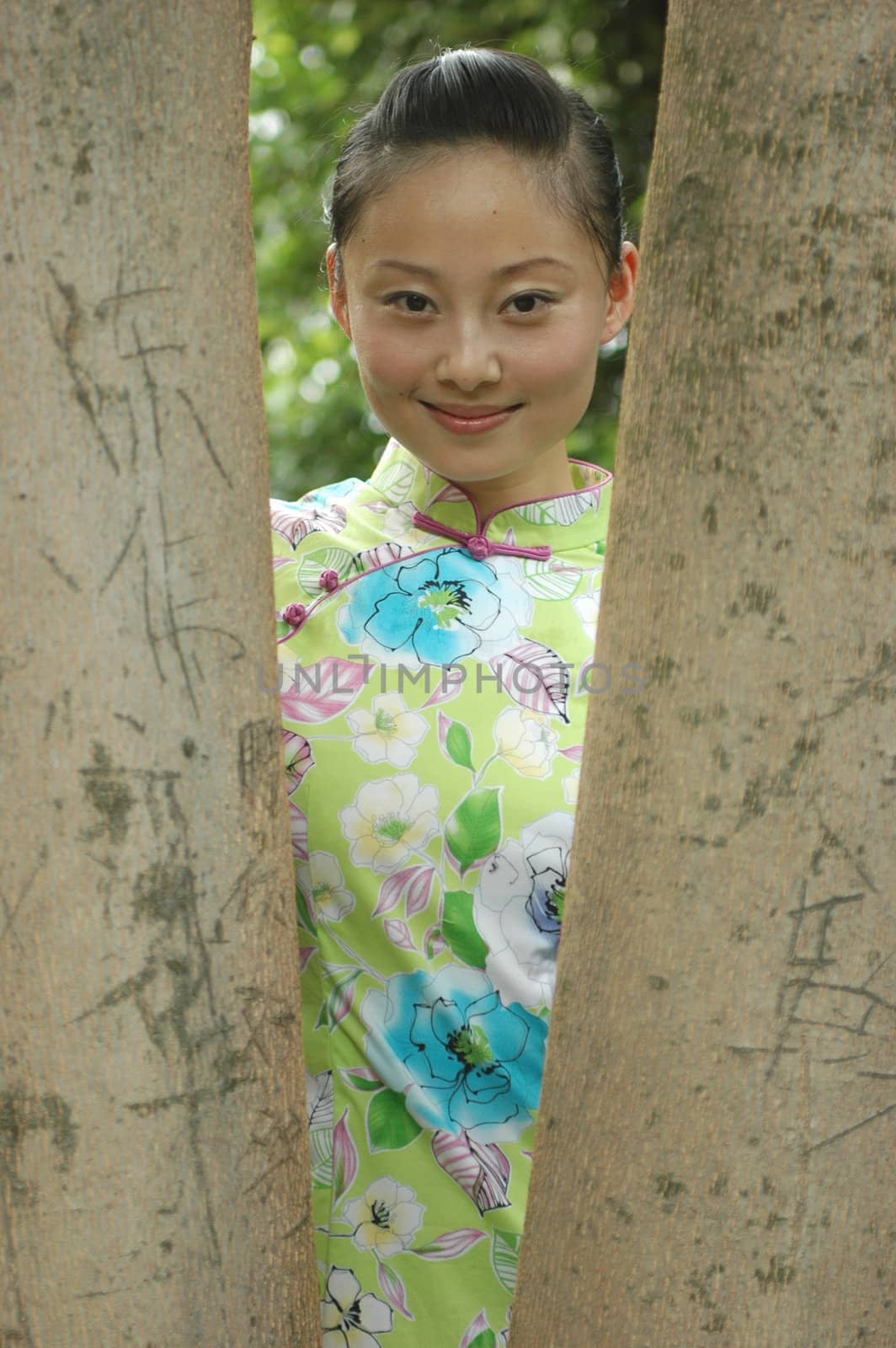 Chinese girl standing between trees in park.