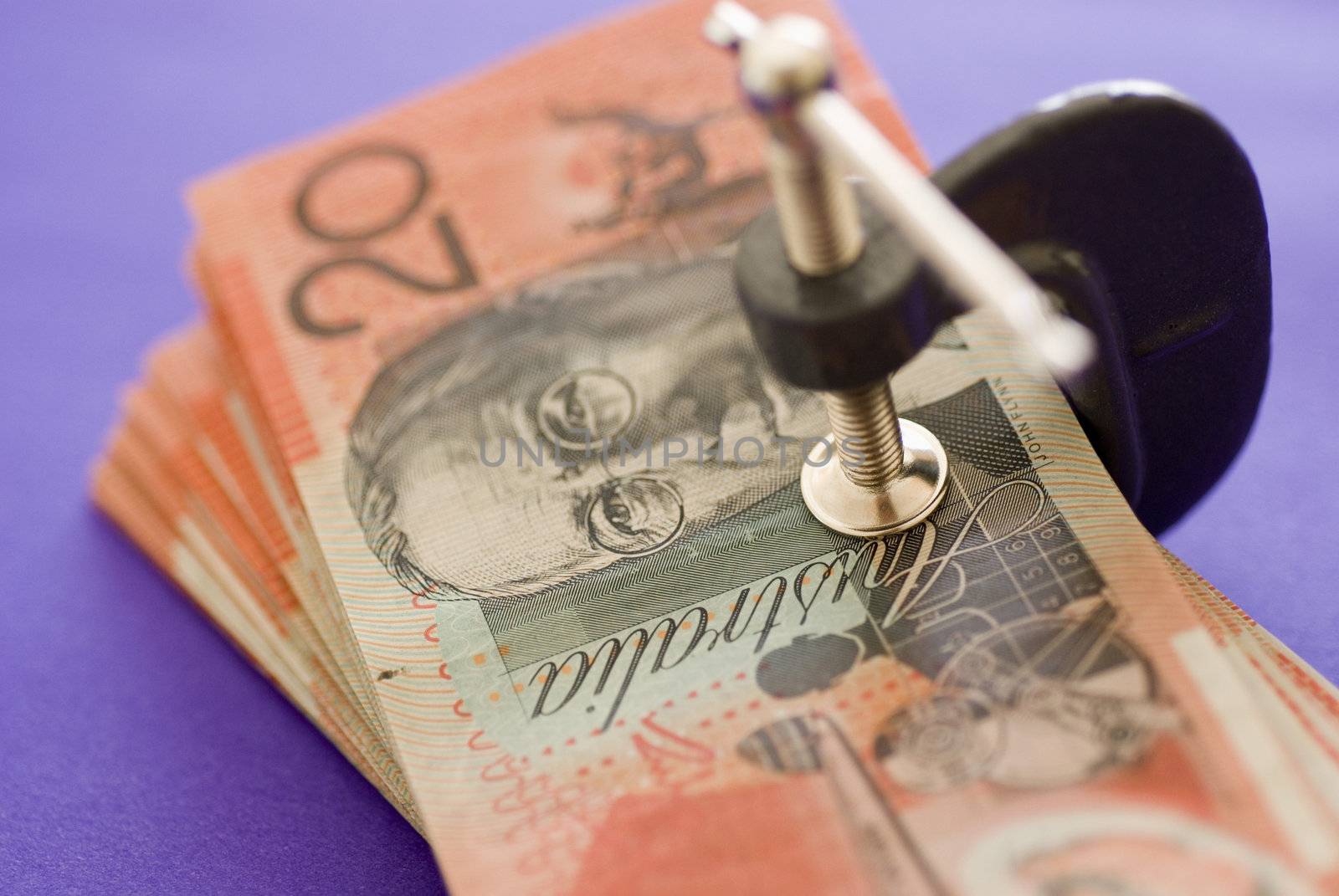 a wad of australian 20 dollar notes pressed in a G clamp