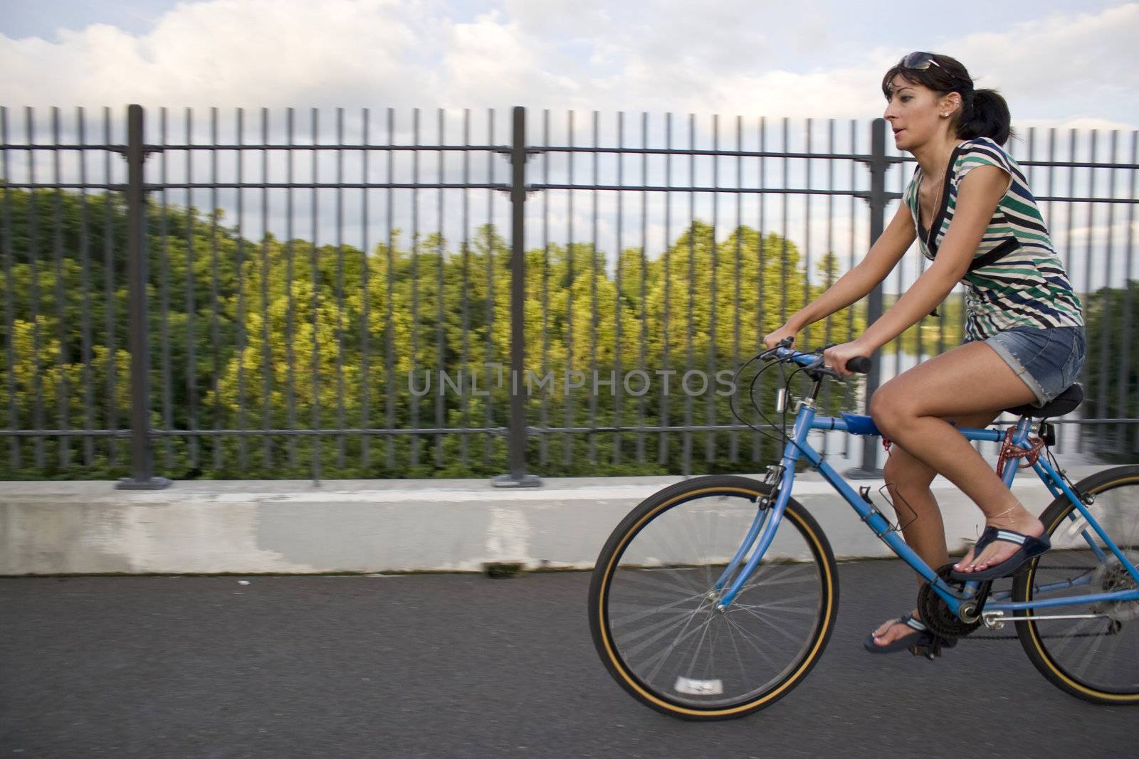 A young woman riding a bicycle across the bridge