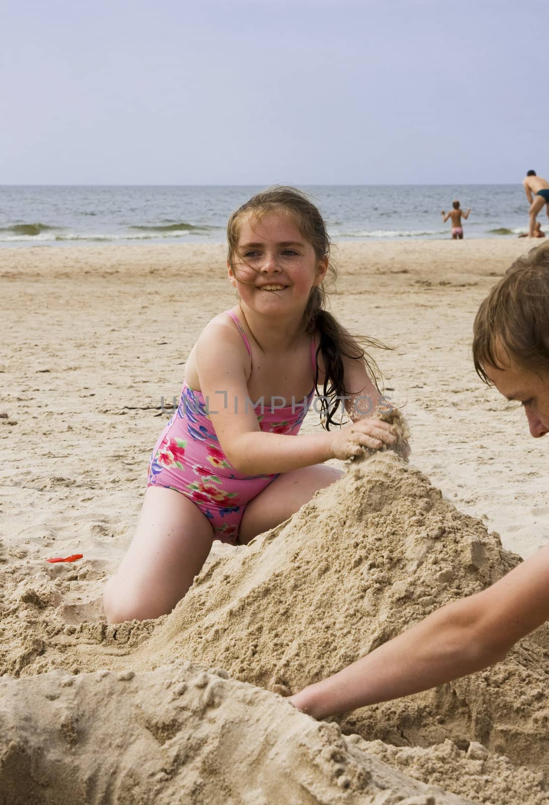 Happy smiling girl playing on beach sand. Lithuania, coast of Baltic sea