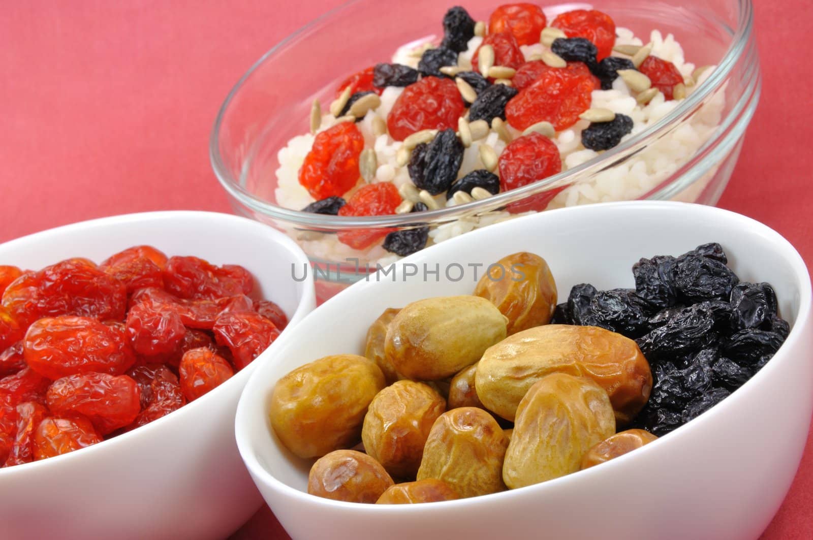 Three Bowls with Boiled Rice and Dried Fruit on Red Background