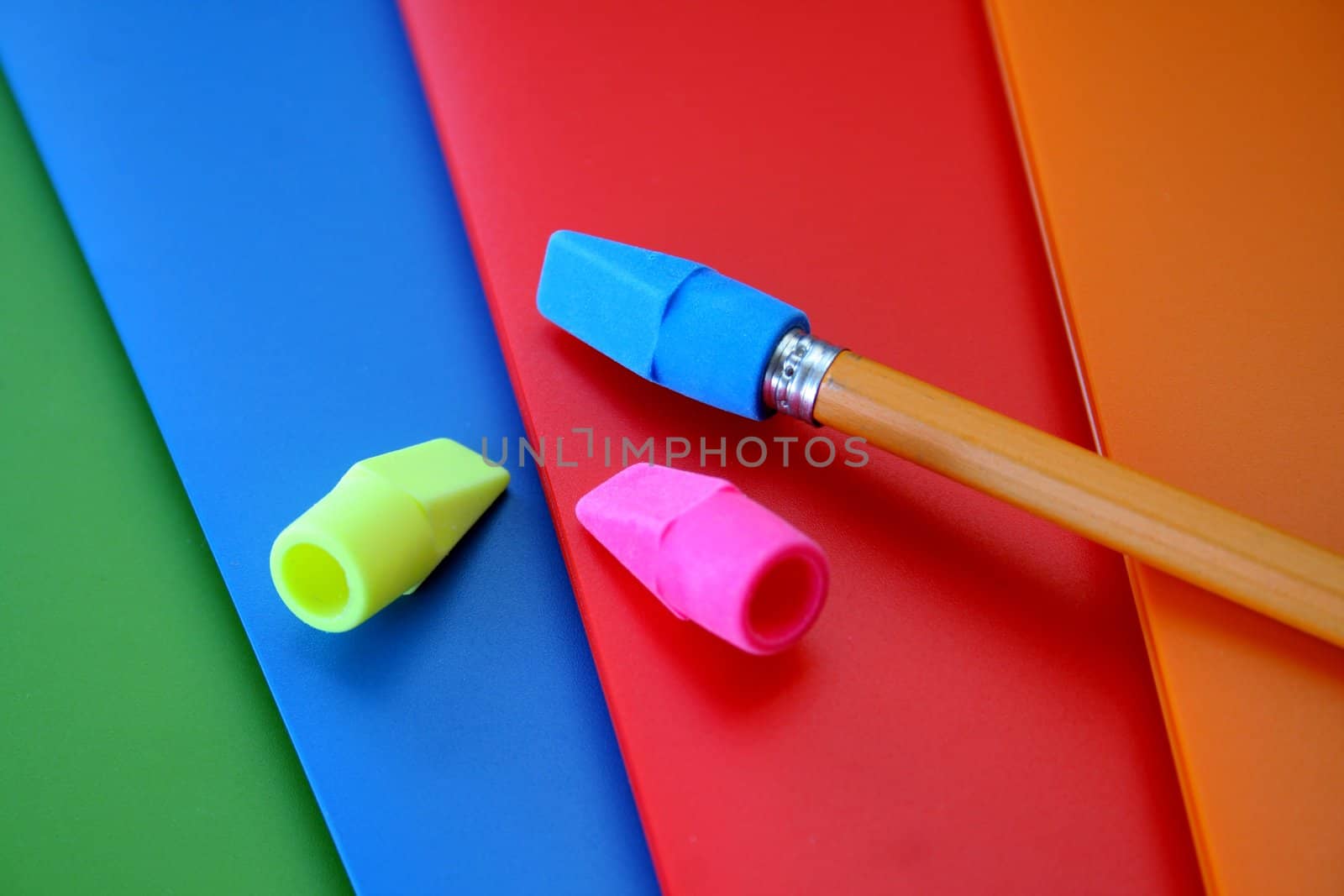 four colorful folders along with erasers and a pencil.  Used a selective focus here with it being on the pencil and blue eraser.