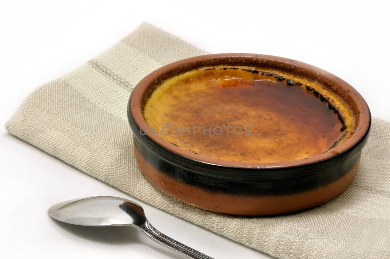 French creme brulee served in an earthenware dish on a napkin