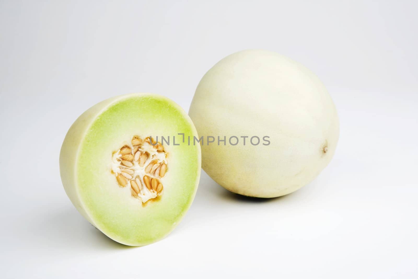 Two halves of a honeydew melon on a white background