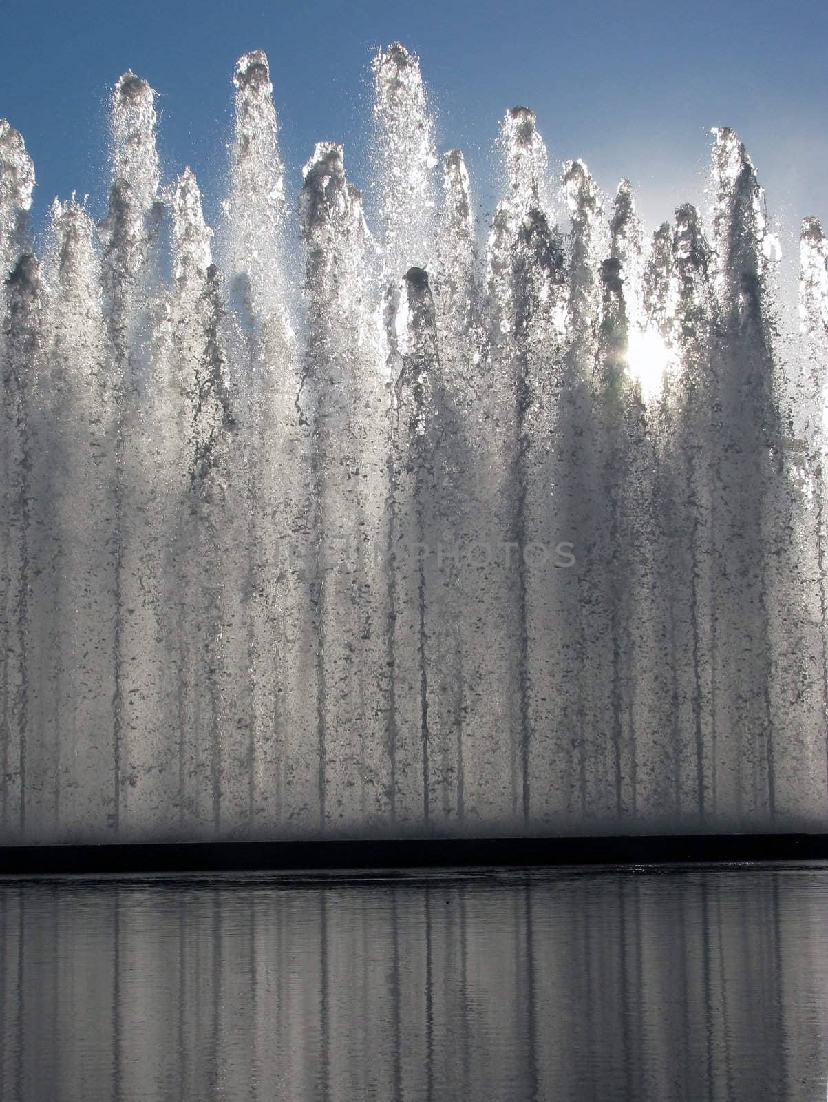 The sun through a fountain and reflecting pool.

