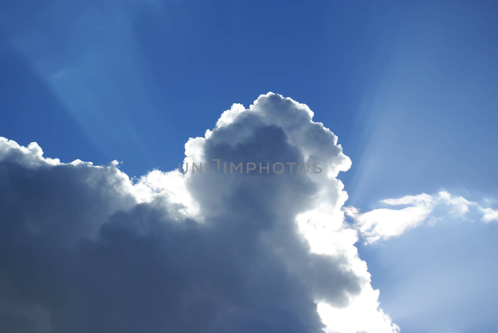 Blue sky with rays coming from behind a cloud.