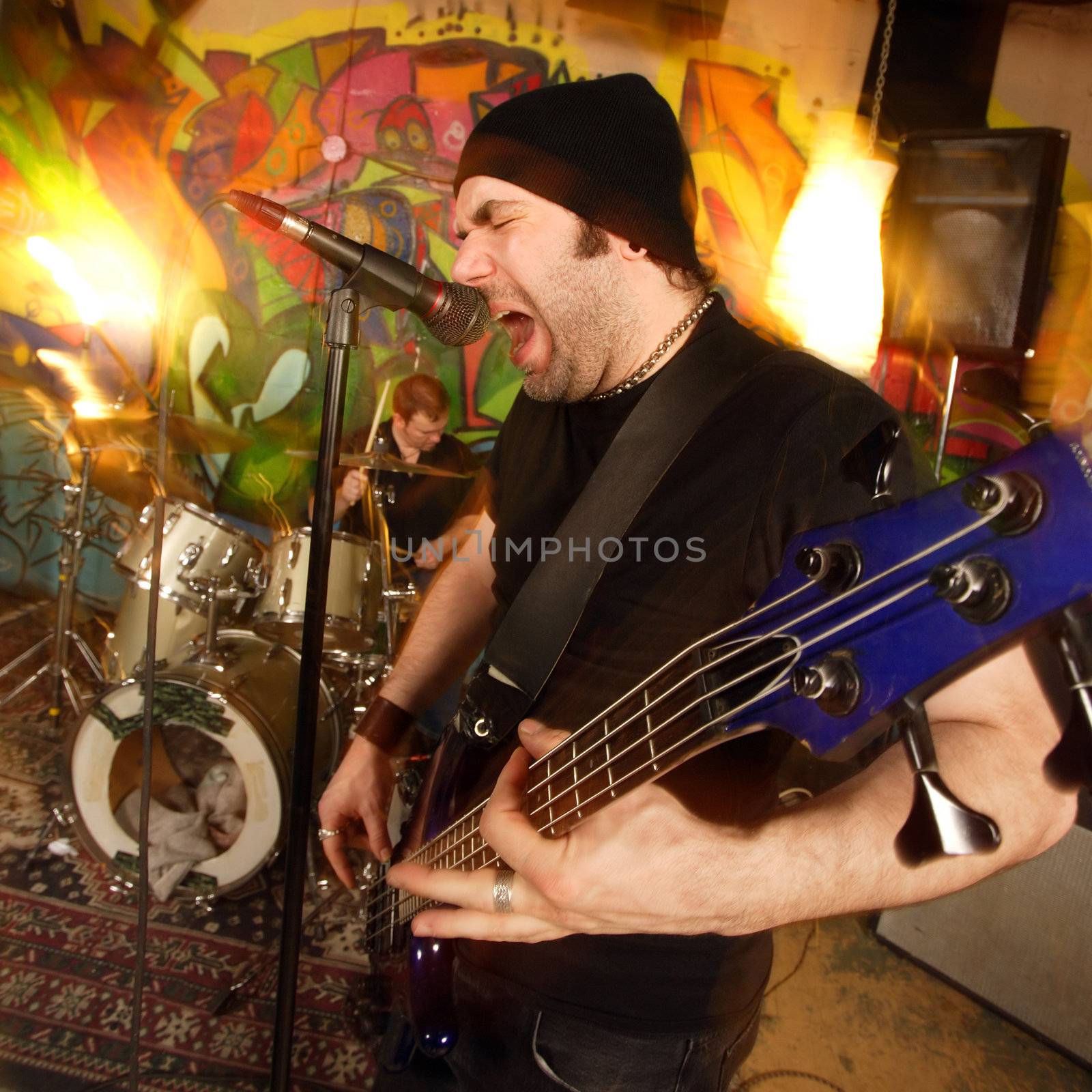 Heavy rock band with bassist and drummer playing. Shot with strobes and slow shutter speed to create lighting atmosphere and blur effects.
