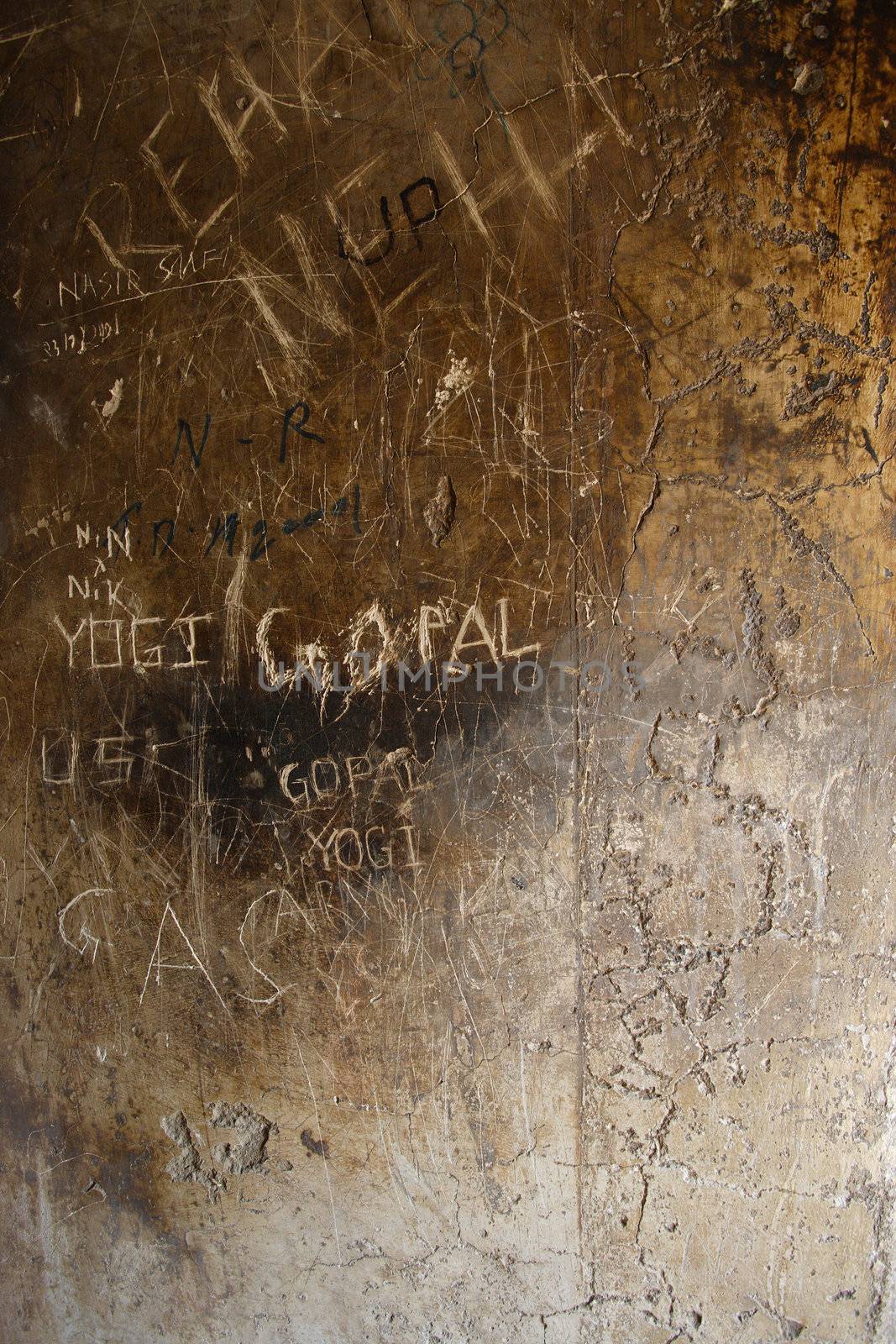 A wall of a temple in india that has had visitors scratch their names into the stone surface.
