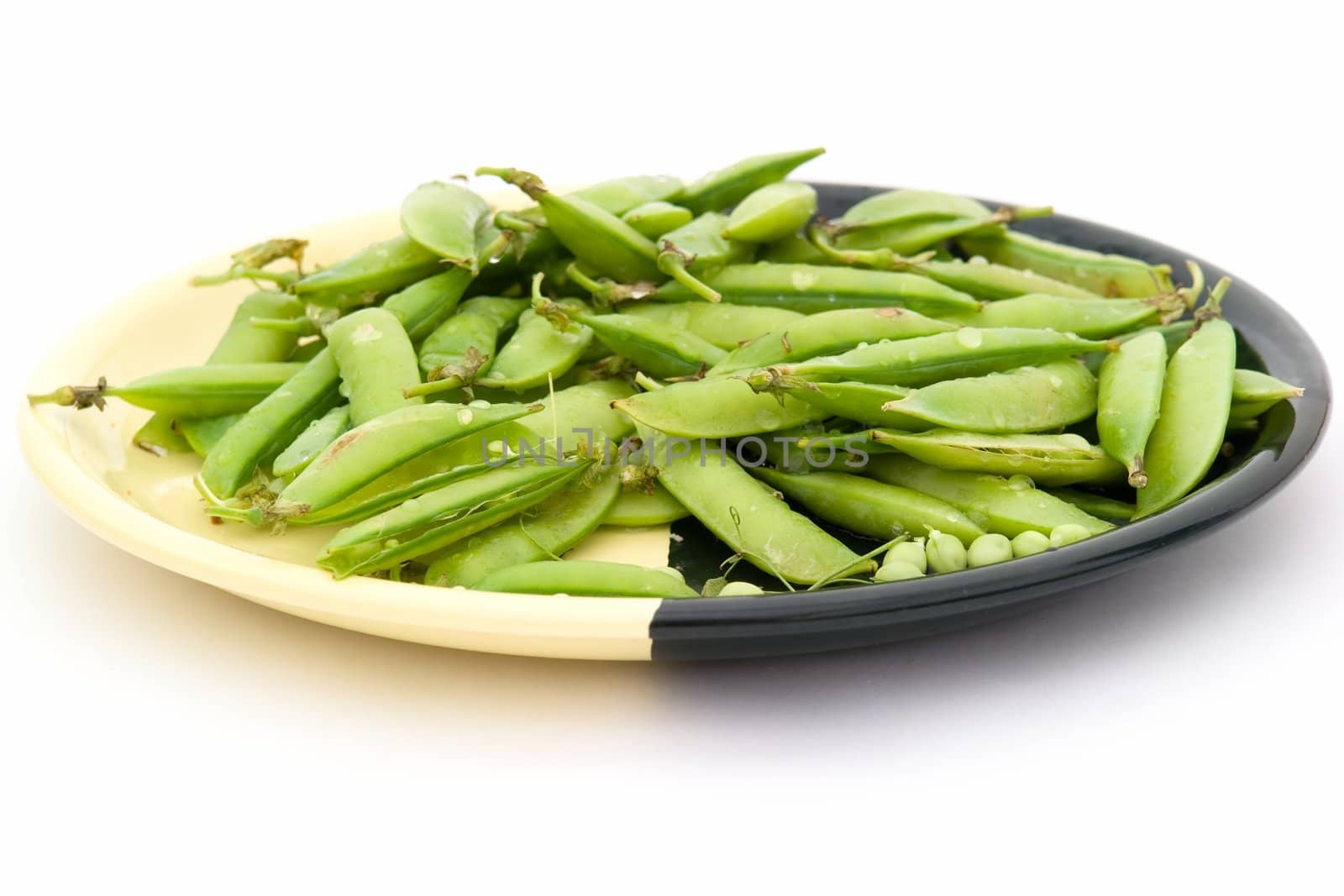 Peas pods on a plate on a white background