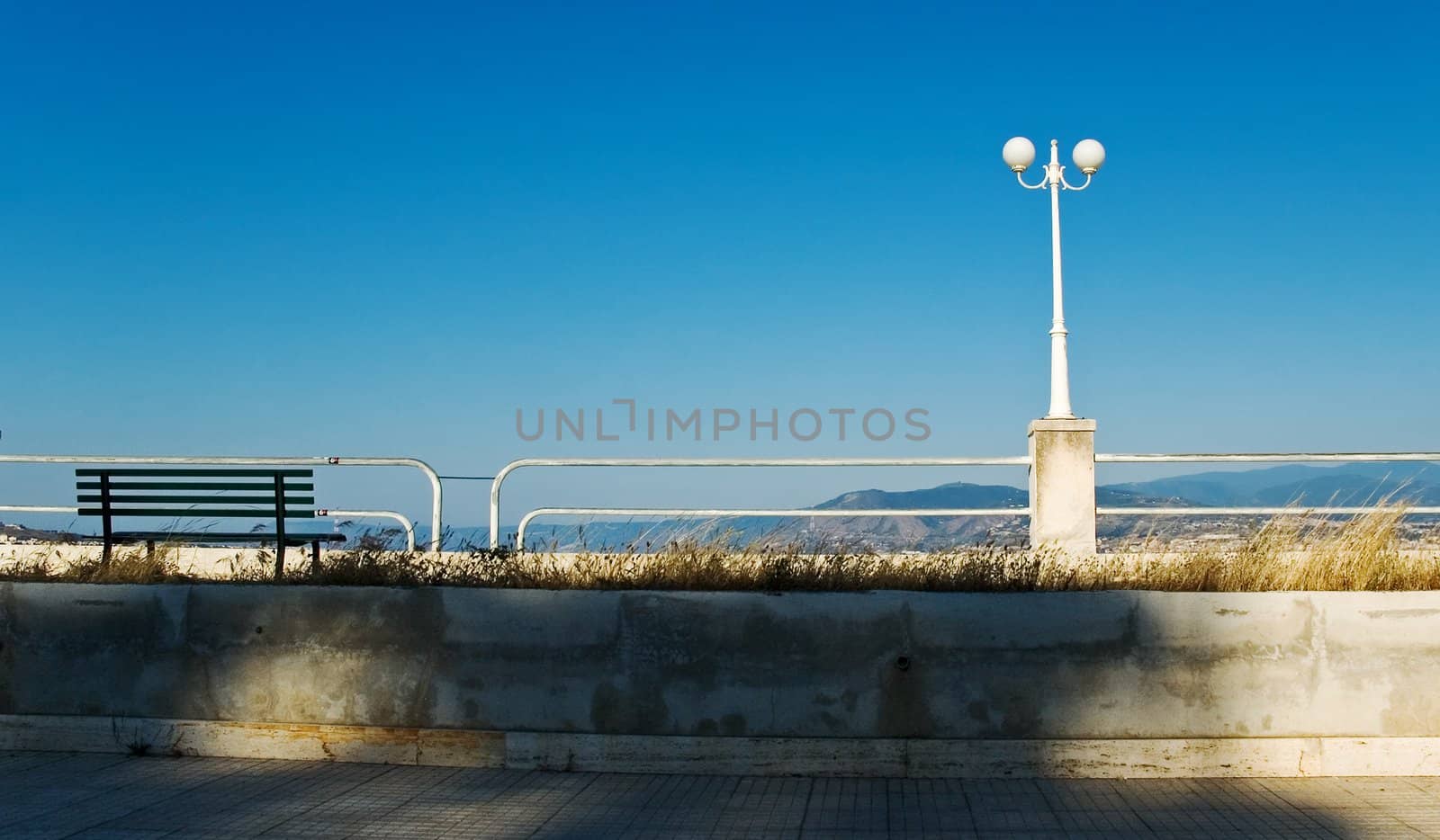 Bench and streetlight on the waterfront with blue sky and copy space