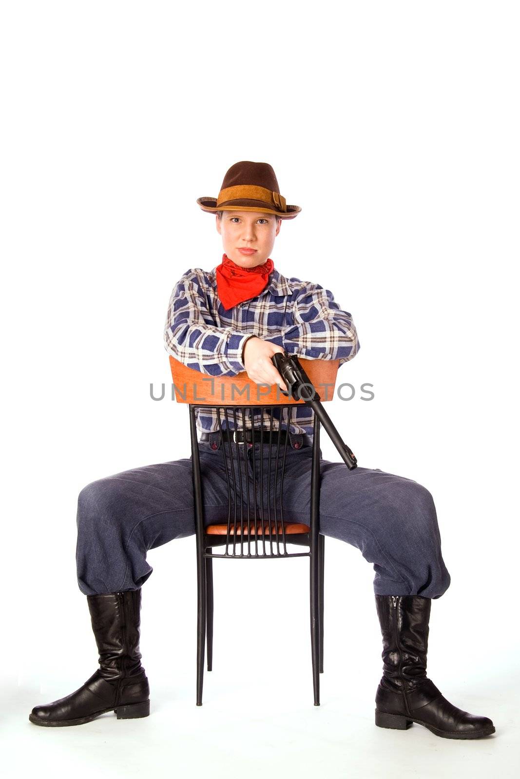 Resolute cowgirl with gun sitting on the chair (isolated on white)