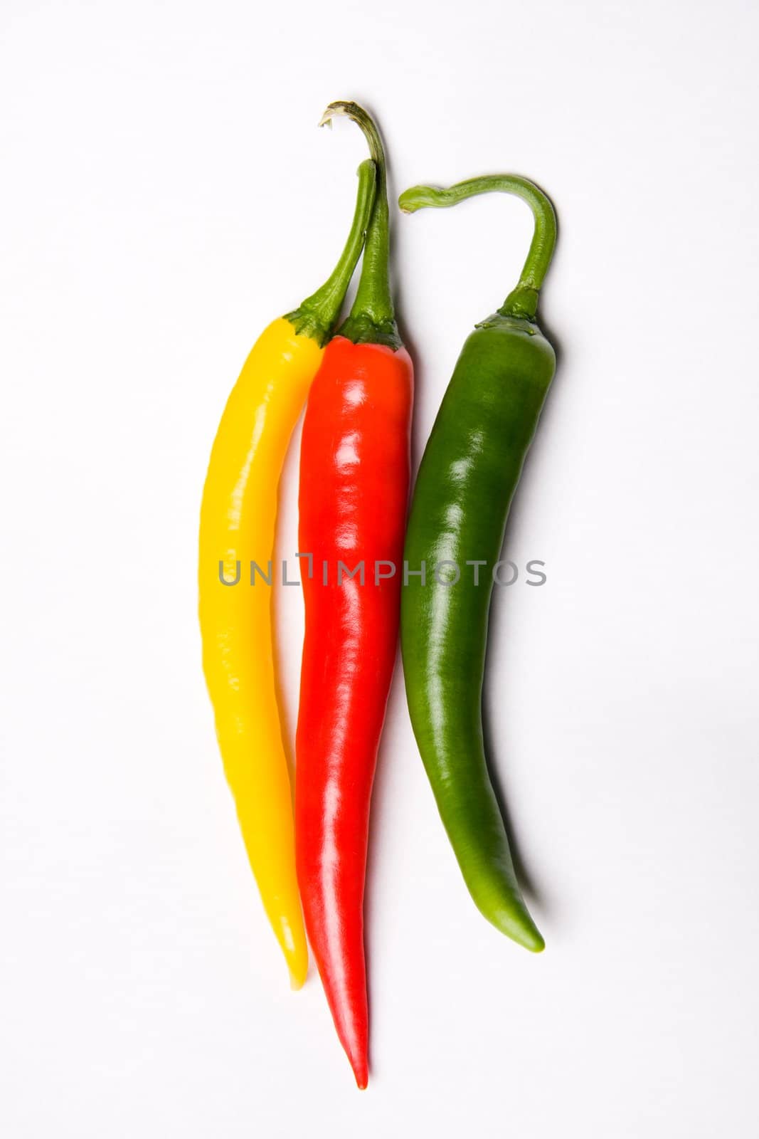 Three chili peppers, red, yellow and green on white background