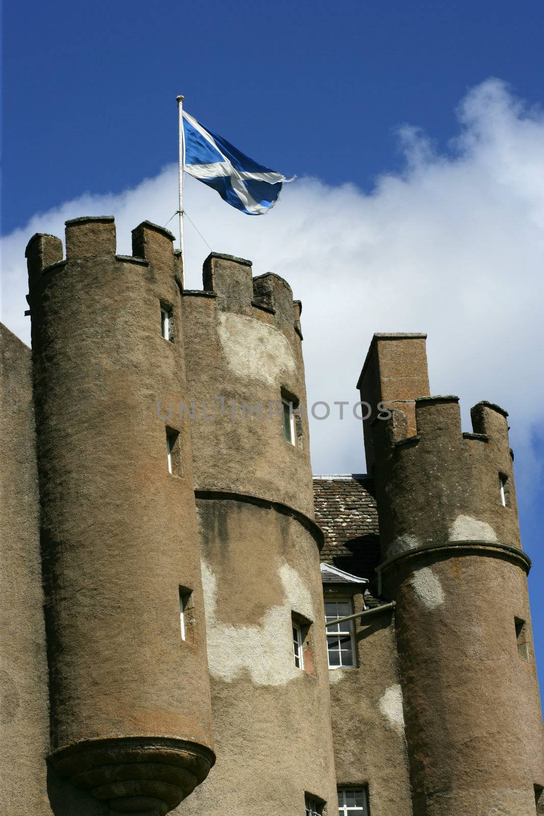 Turrets of a castle in Scotland with Scottish flag blowing in the wind.

