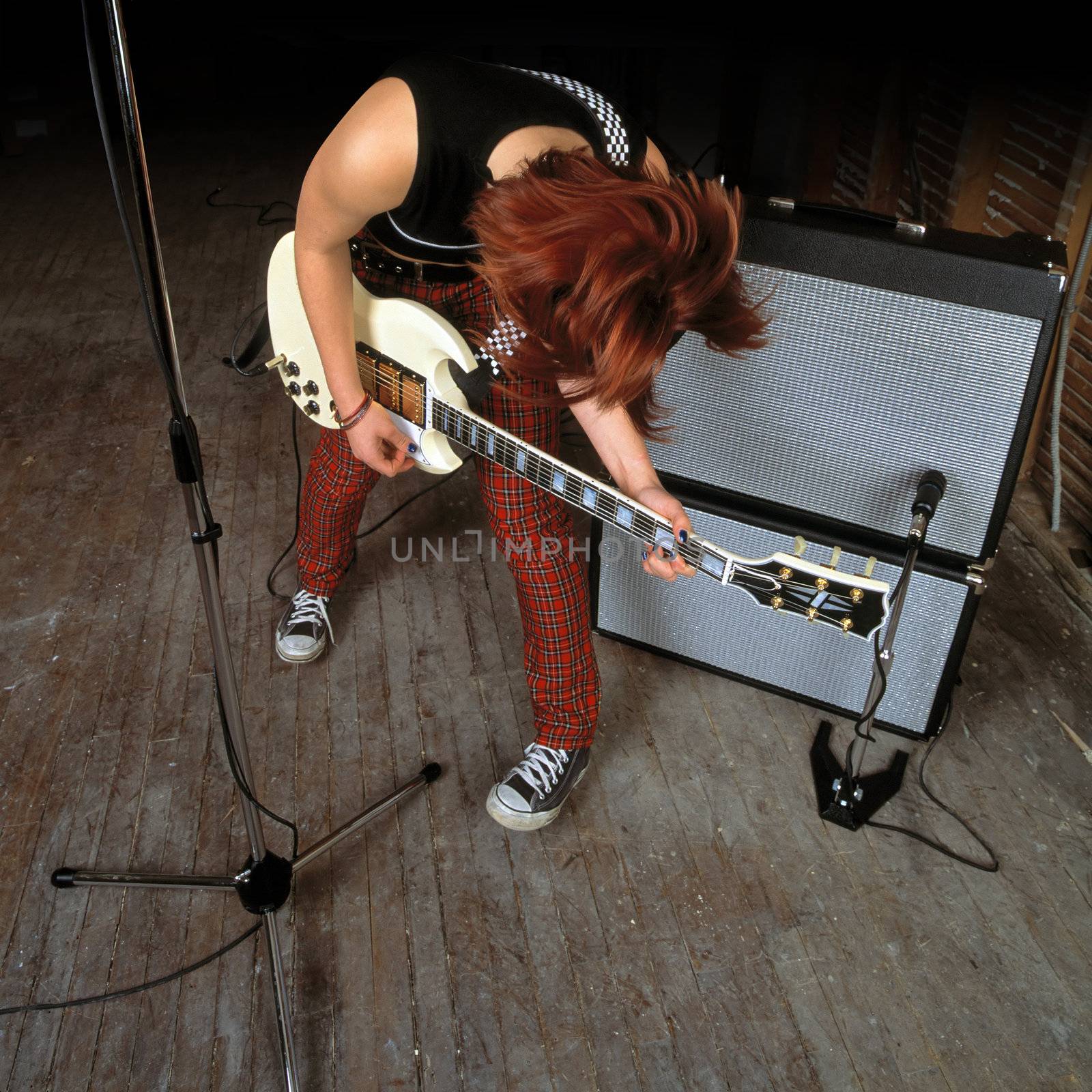Image of a female guitarist playing in front of an amplifier.
