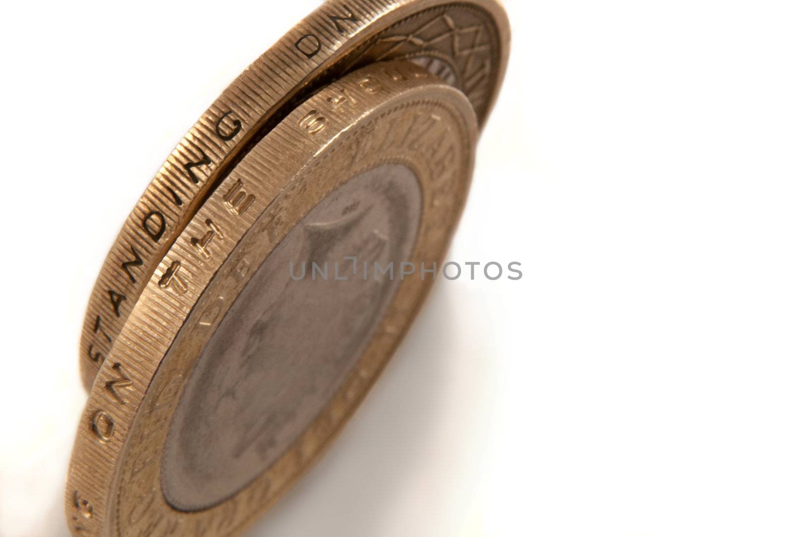 Close up capturing a selection of British two pound coins arranged over white.