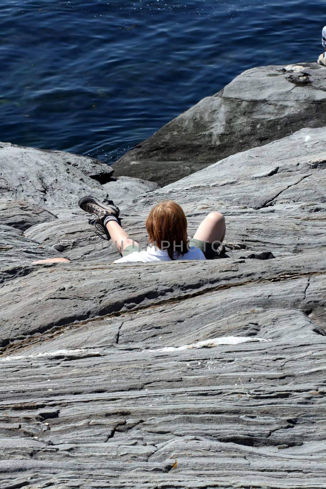 a young man, fallen on the granite cliffs next to the ocean
