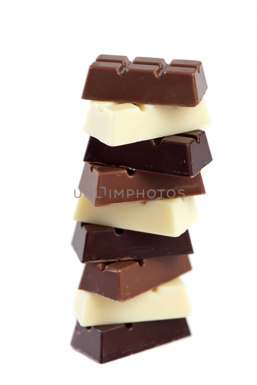 Pile of various colored chocolates; white, brown and dark chocolate