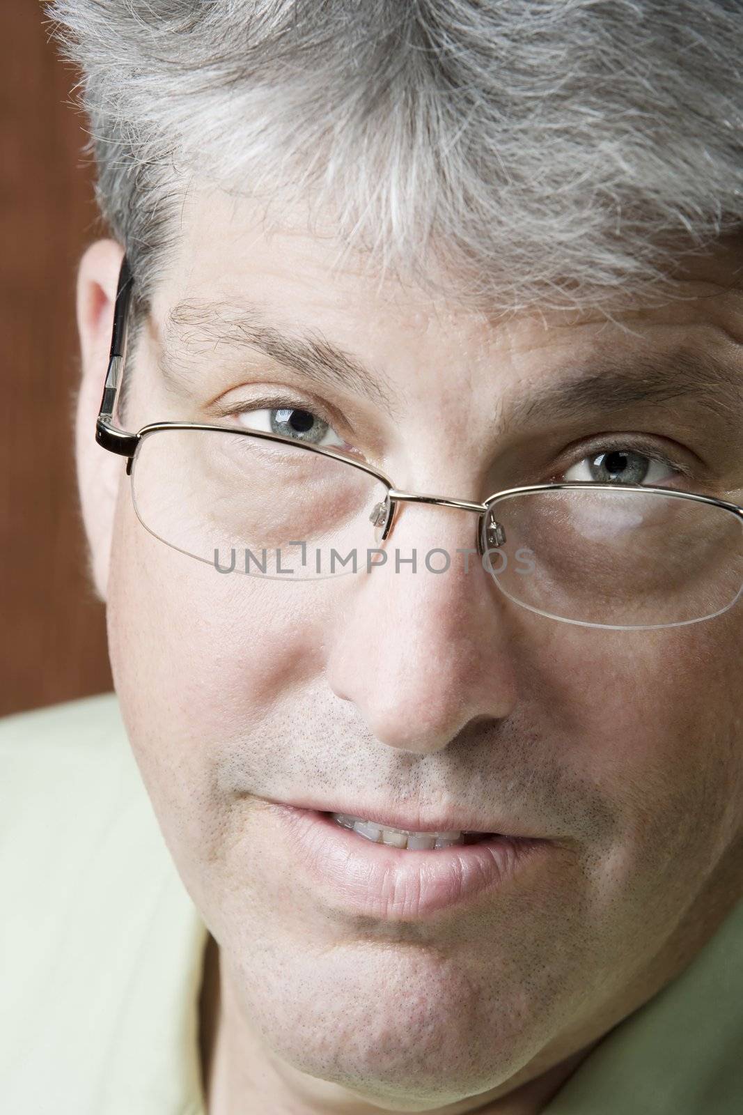 Man looking over glasses in front of a gold background