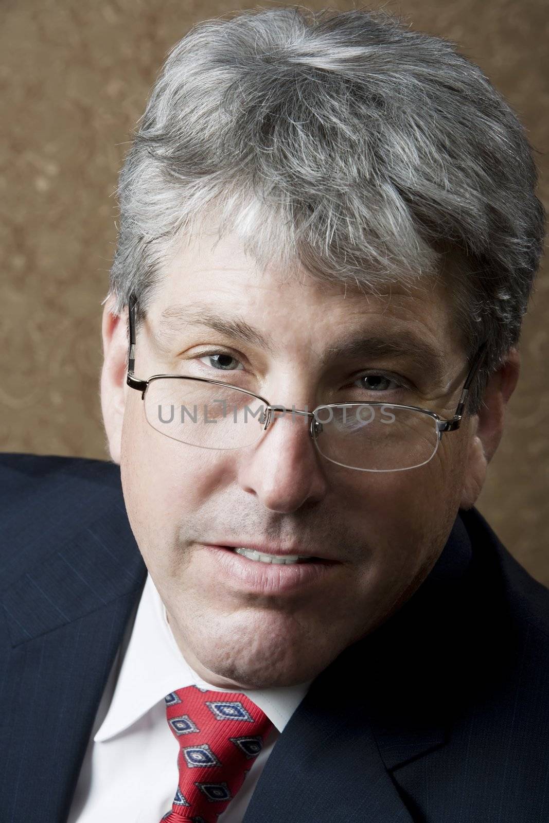Corporate executive looking over glasses in front of a gold background