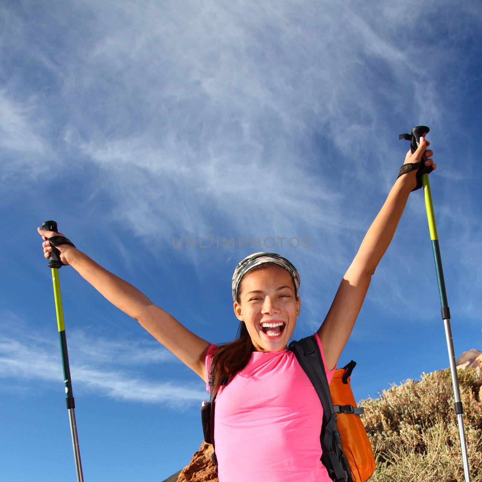 Happy woman hiker holding her arms in the air in a feeling of success having reached the summit. From a hike / backpacking trip in the beautiful  volcanic landscape on the volcano, Teide, Tenerife.