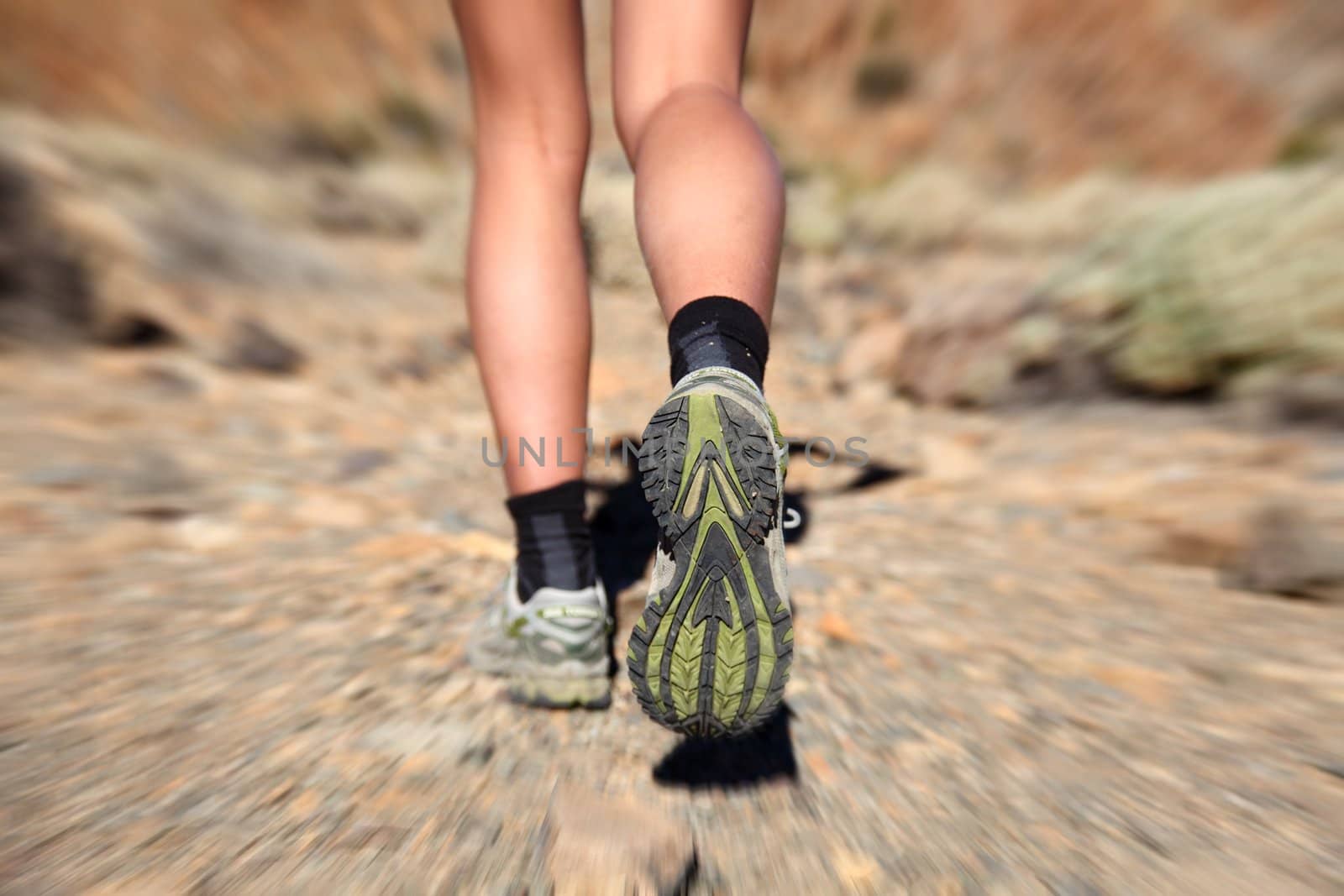 Woman running on trail. Zoom motion blurred closeup of woman trail running in desert on the volcano Teide, Tenerife. 