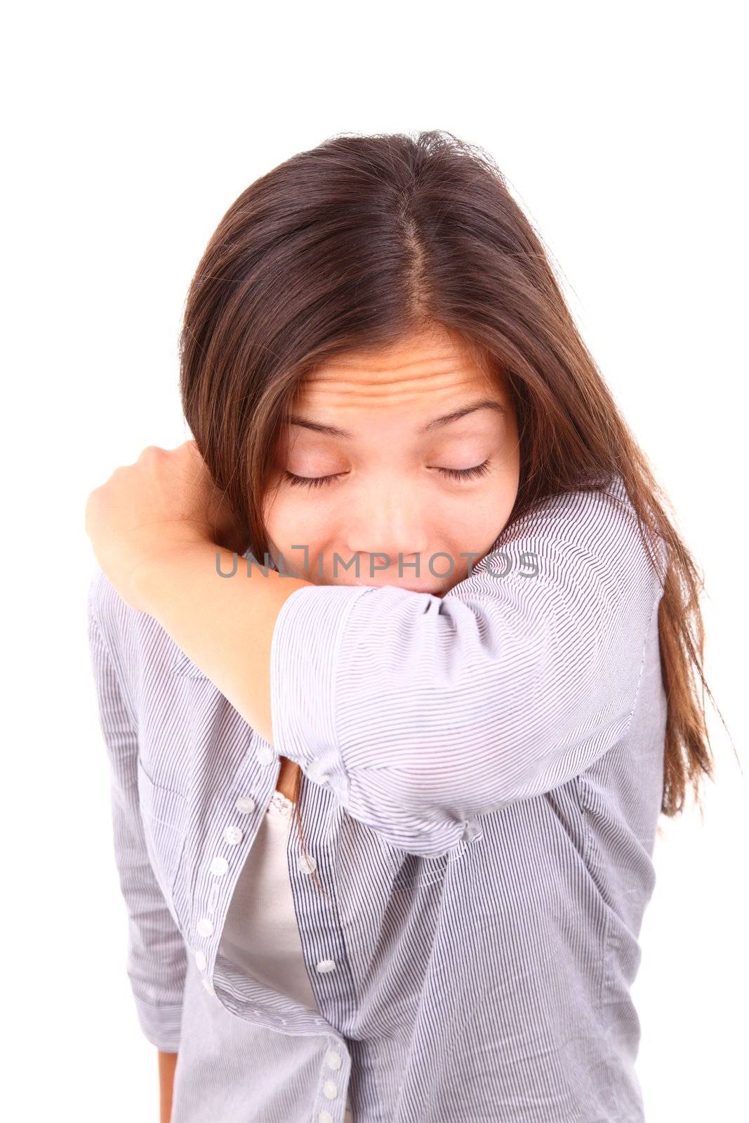 Woman having the flu and sneezing on her sleeve in the elbow crook of her arm. Isolated on white background.