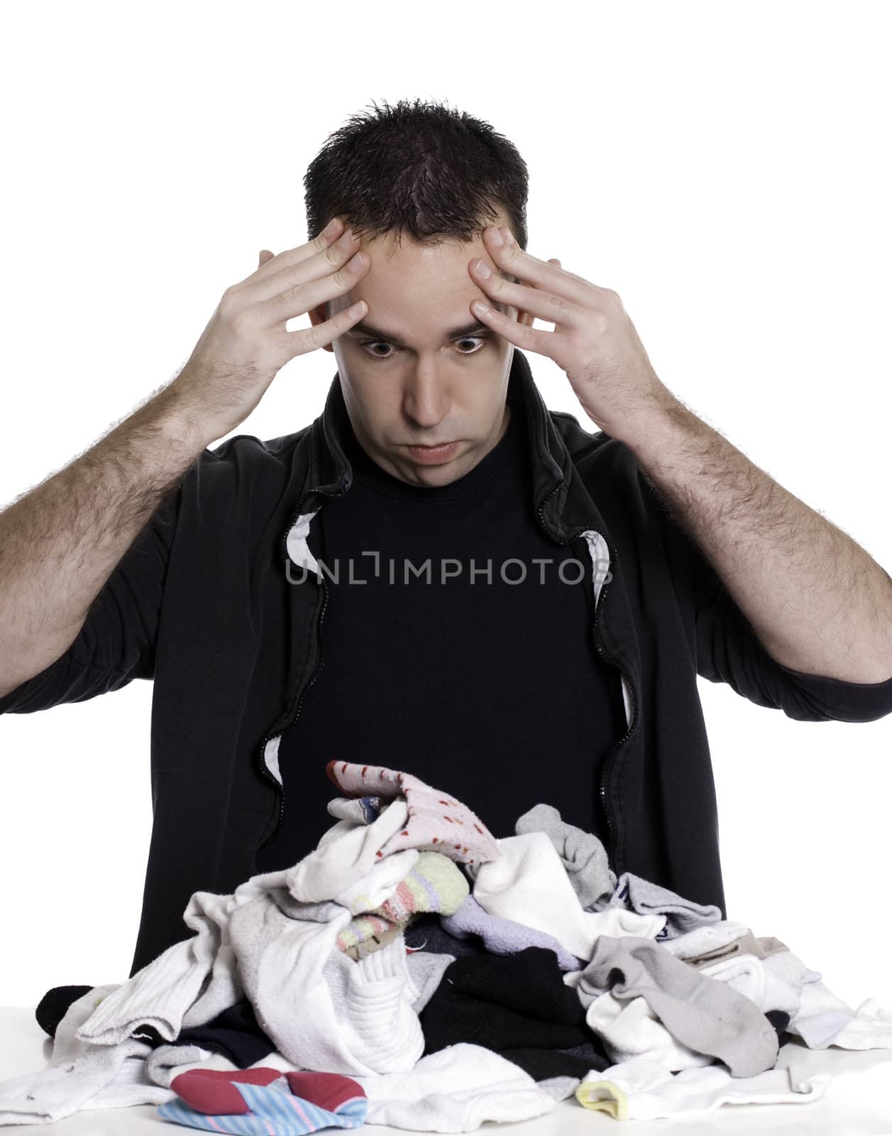 A young man looks frustrated at having to sort laundry or socks, isolated against a white background.
