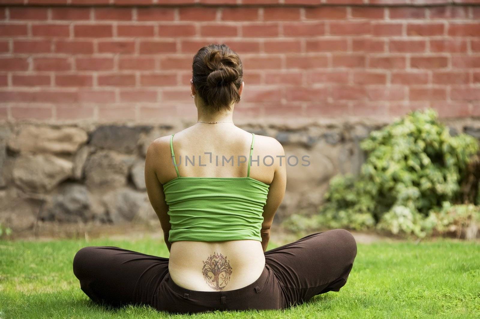Back of woman with a tattoo sitting on grass
