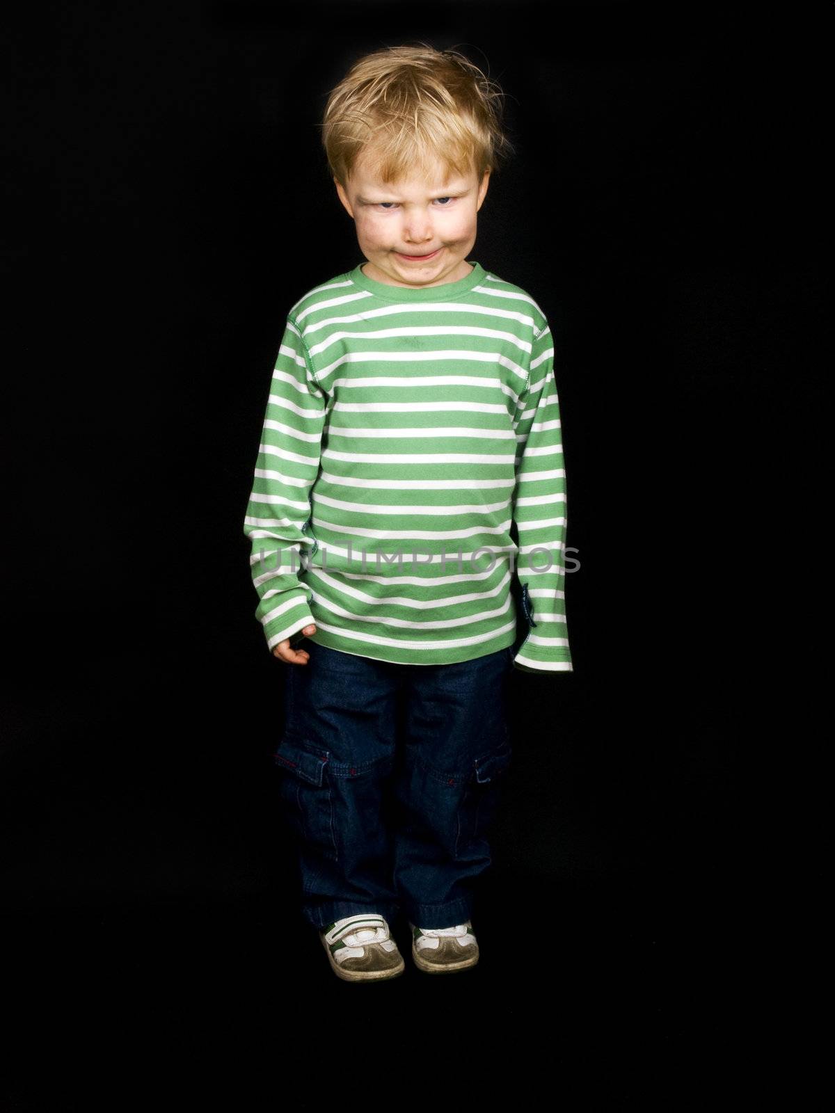 Little boy making scare face on black background. Boy have blue eyes and blond hair and have a bit of dirt on his face