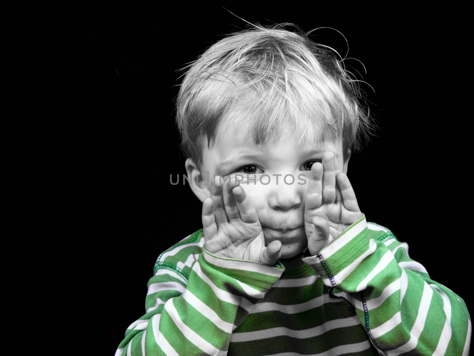 Litlle boy showing hands on black background, monochrome picture with only color green