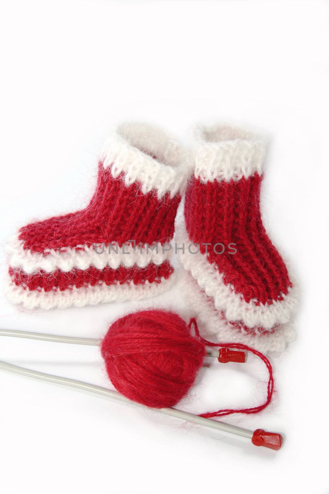 Bound baby's bootees for baby's with a ball of red yarn and knitting