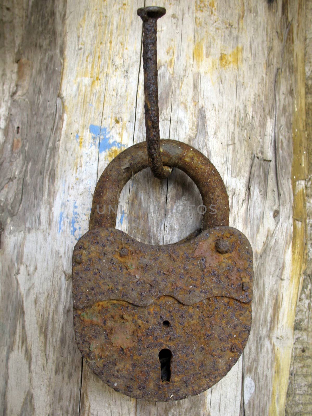 Old rusted padlock on a nail.