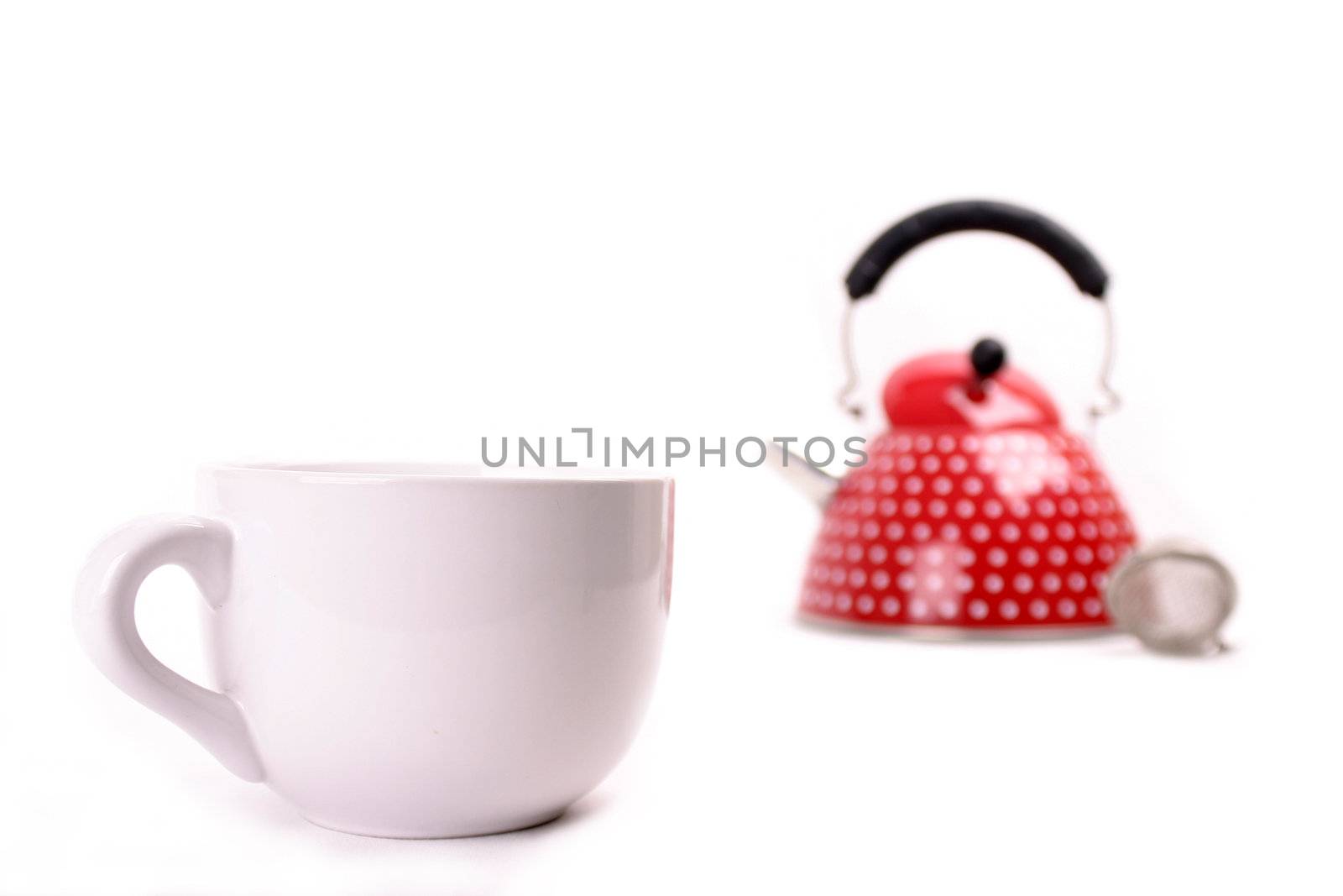 Cup in the foregrund and red teapot in the background