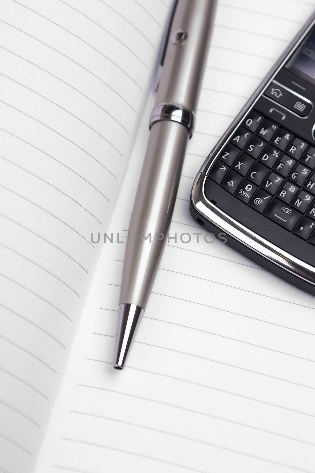 Pen and cellphone on top of a notebook.