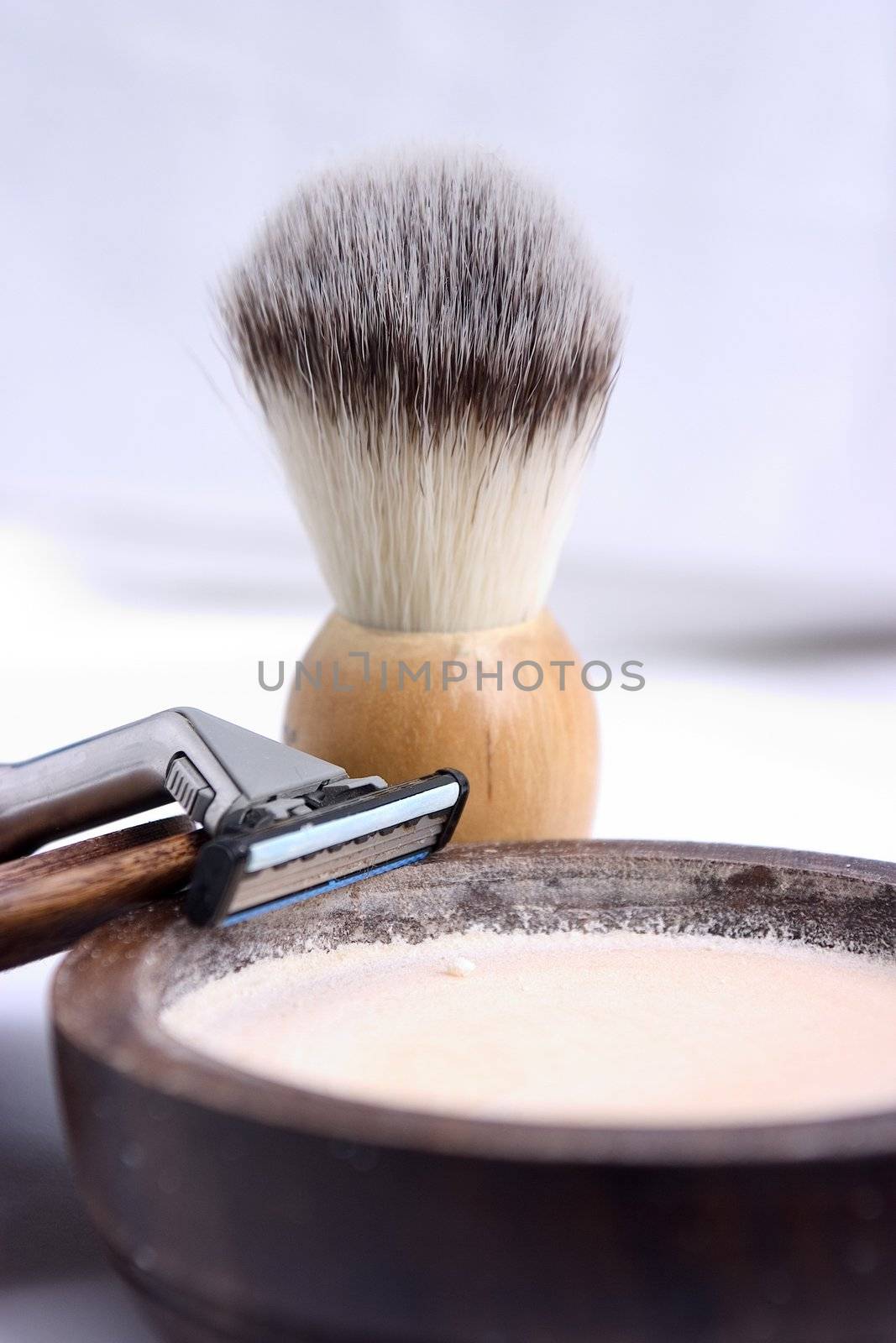 Razor, shaving brush and soap on a diffuse background.