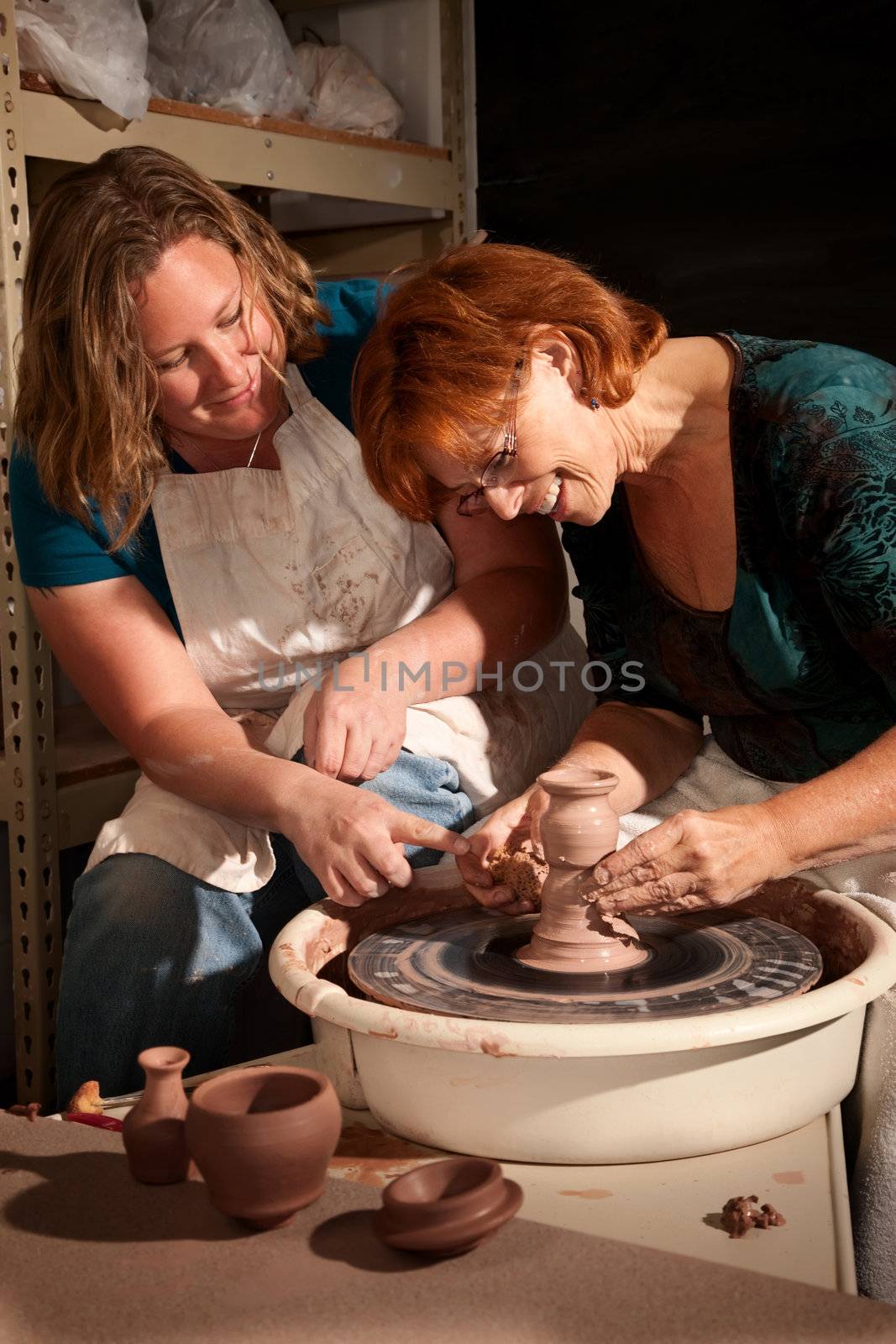 Teacher and student in clay studio working at the wheel