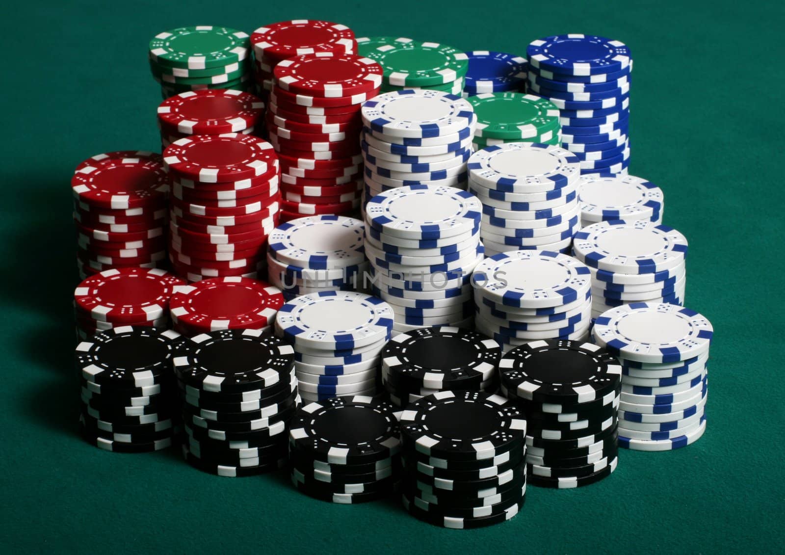 Large amount of poker chips stacked on a green felt pokertable