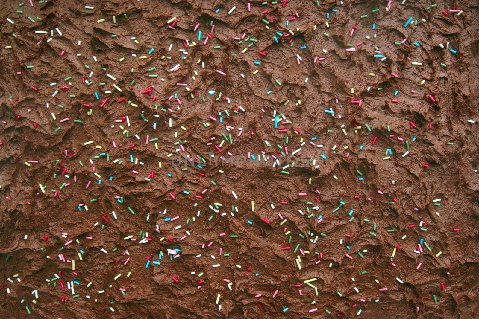 Delicious chocolate cake background with frosting and sugar confetti