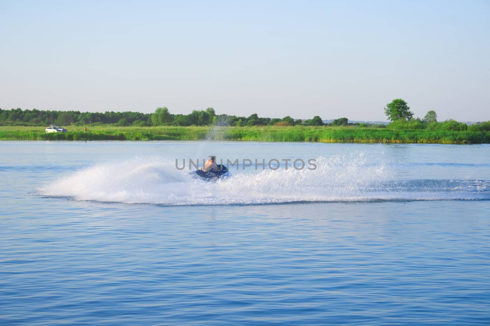 The man goes for a drive on a hydromotorcycle on lake, doing waves