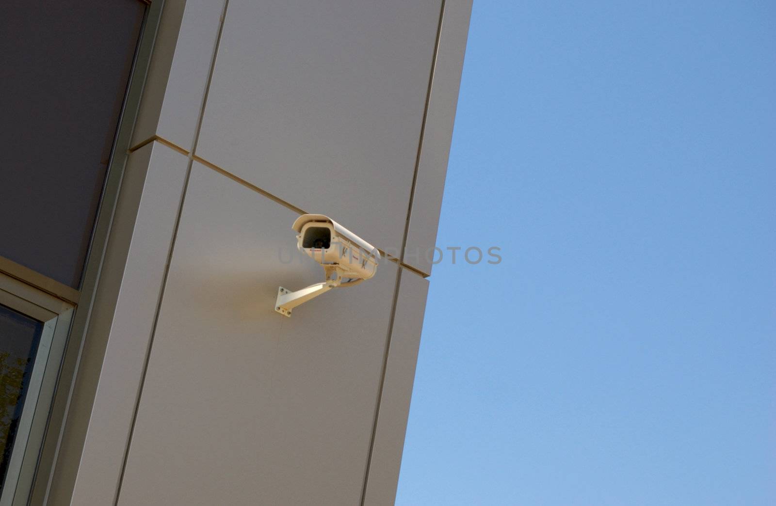 video camera (video surveillance) at front of new modern office building against sky